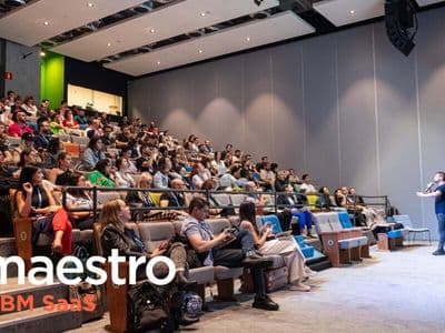 Audience watching a presenter in a modern auditorium, with "maestro ABM SaaS" logo in the foreground. The tone is professional and engaging.