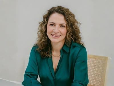 Simonetta Roma, a leadership coach, smiling confidently while sitting at a desk with a laptop.