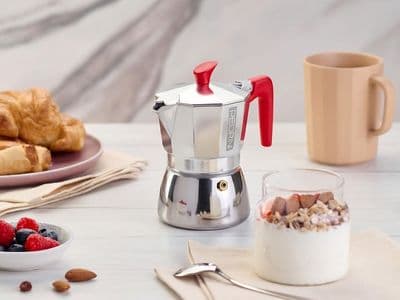 Pedrini moka coffee maker with pastries, yogurt, and berries on breakfast table.