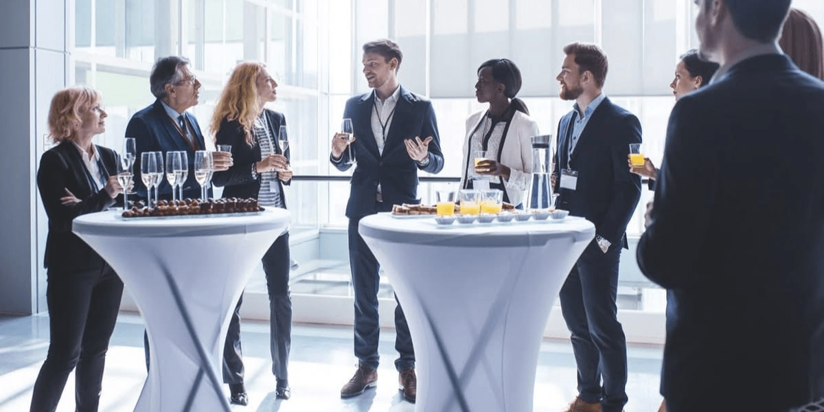 A professional gathering with people talking and enjoying drinks at cocktail tables