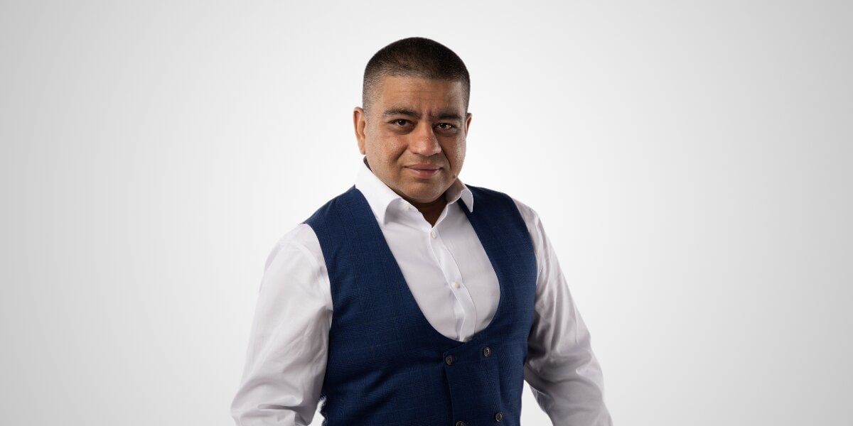 Imran Hussain, a professional and empathetic Fractional CFO, dressed in a white shirt and blue vest.