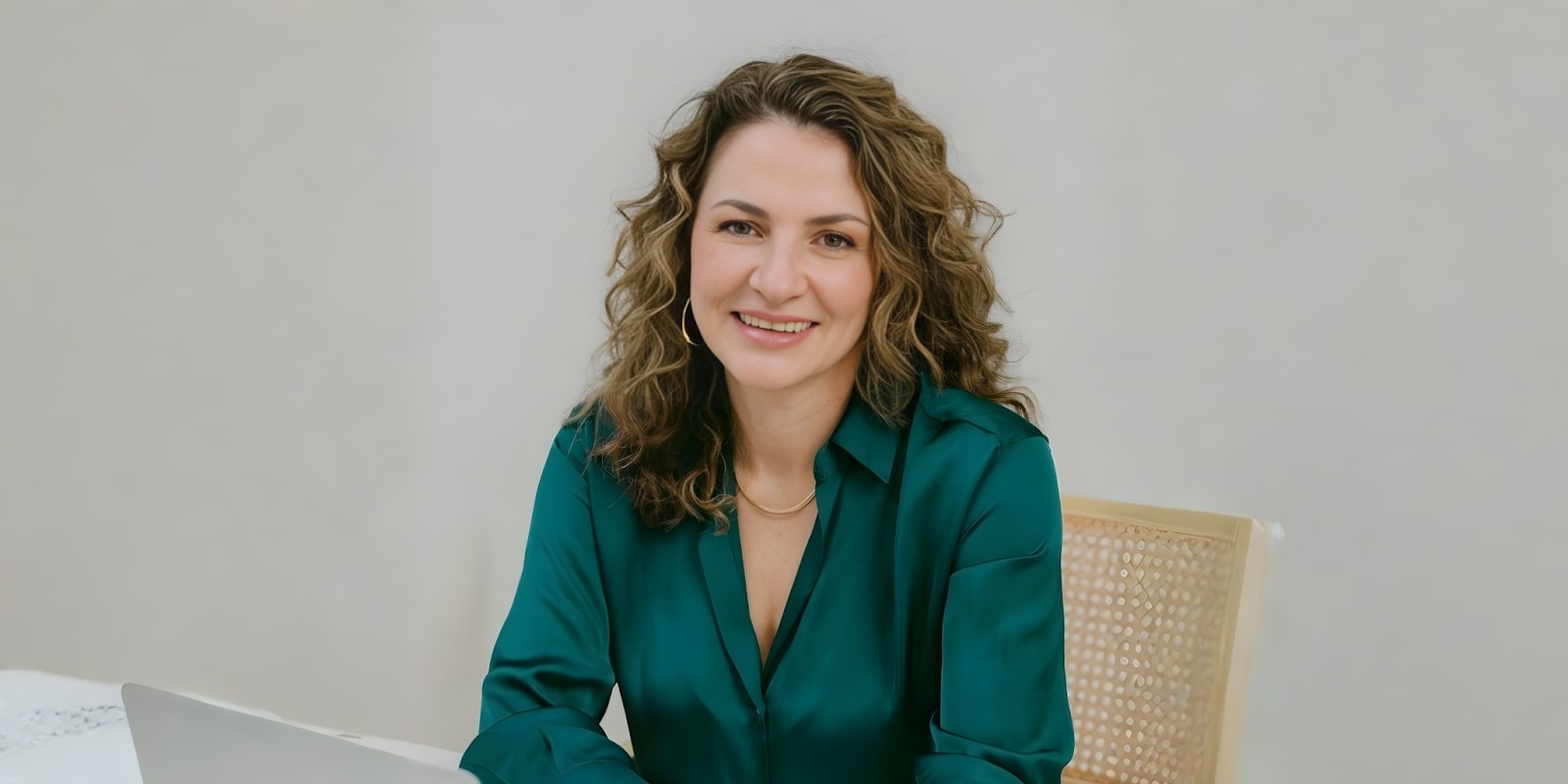 Simonetta Roma, a leadership coach, smiling confidently while sitting at a desk with a laptop.