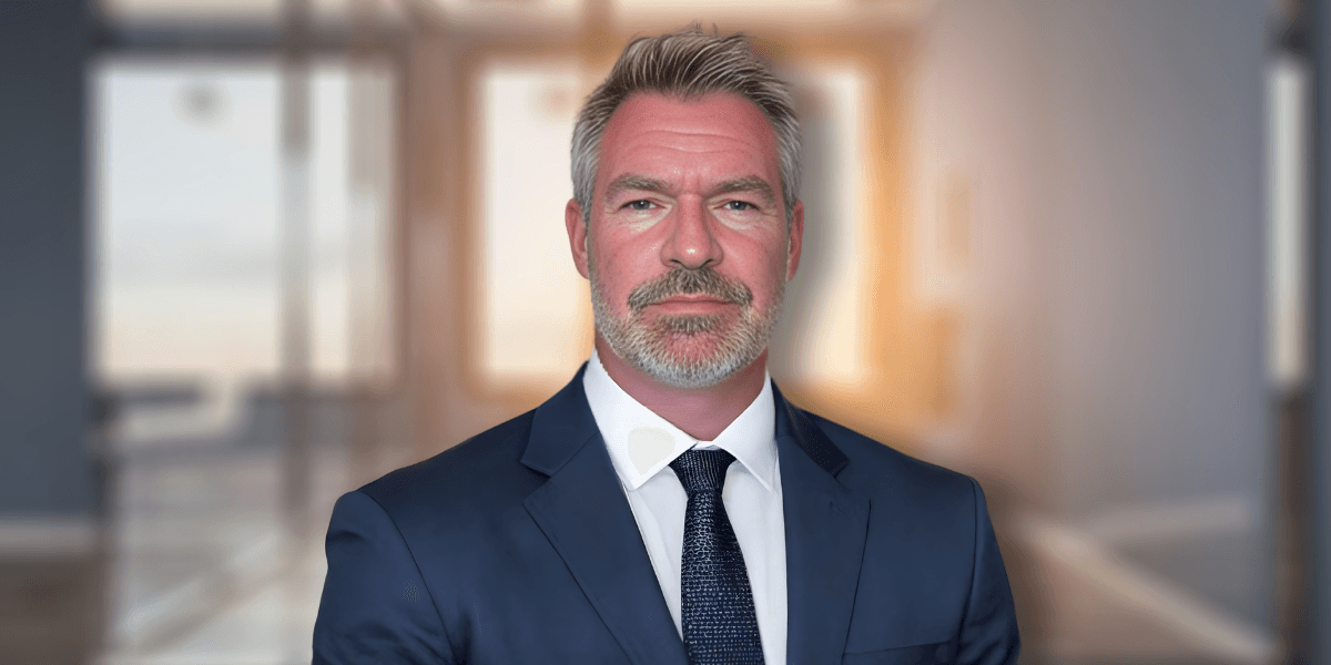 Professional businessman in navy suit with confident expression in modern office setting.