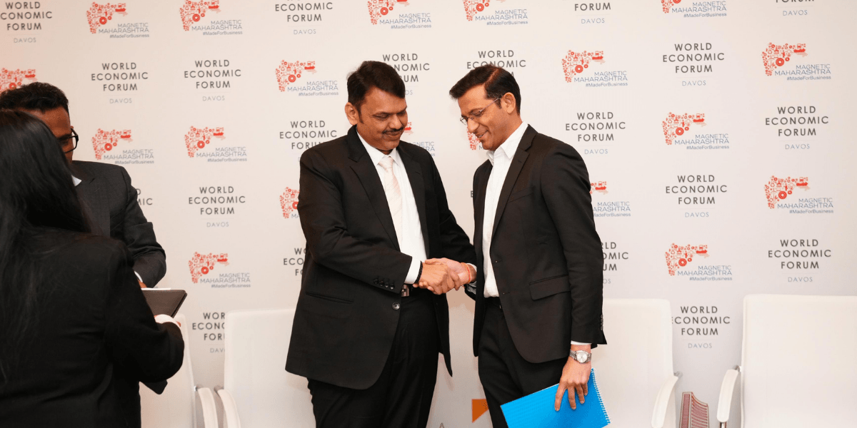 Darpan Jayraj Kale and Devendraji Phadnavis shake hands at the World Economic Forum, announcing AI infrastructure collaboration.