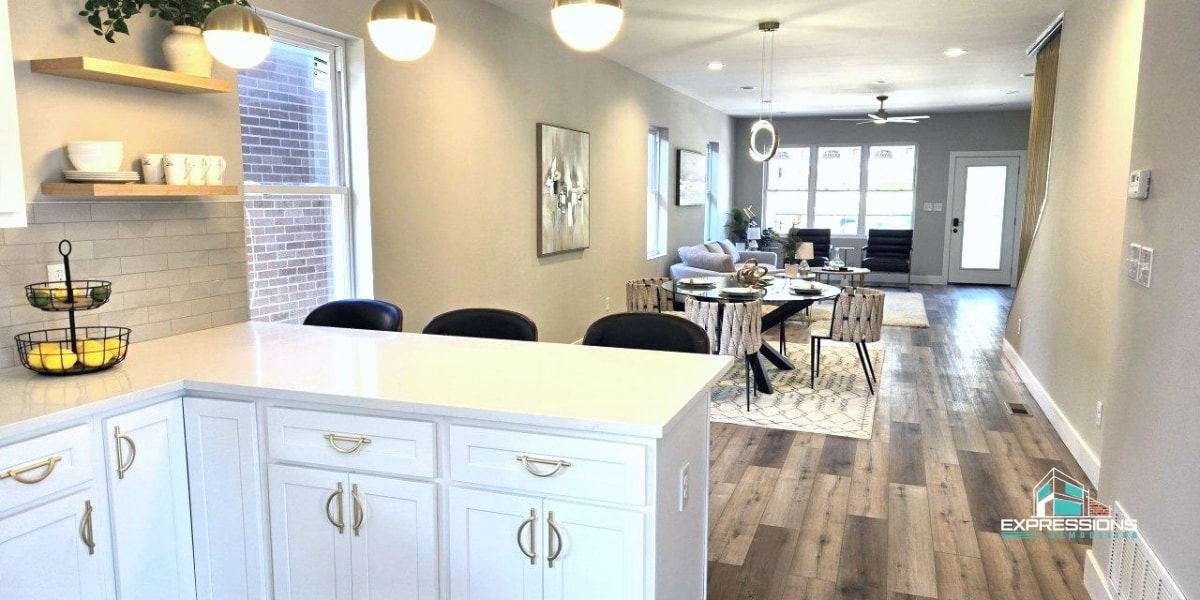 Bright, modern kitchen with white cabinetry, quartz countertops, and stylish pendant lights, overlooking a dining and living area with hardwood floors and contemporary furnishings.