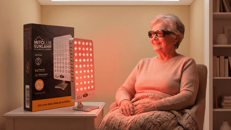 Elderly woman sitting near a red light therapy lamp, looking relaxed and content