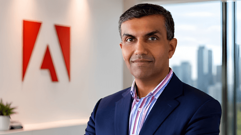 Business professional stands in front of an Adobe logo in an office setting