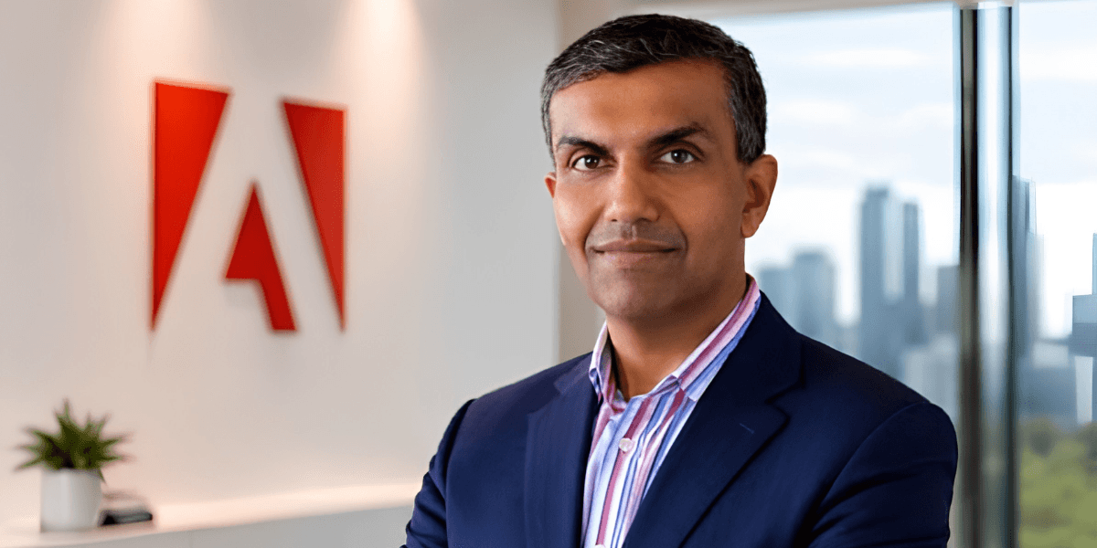 Business professional stands in front of an Adobe logo in an office setting