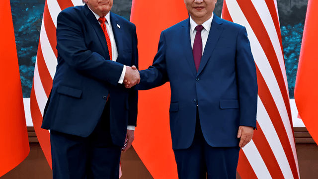 Two leaders shaking hands against a backdrop of flags and a scenic view