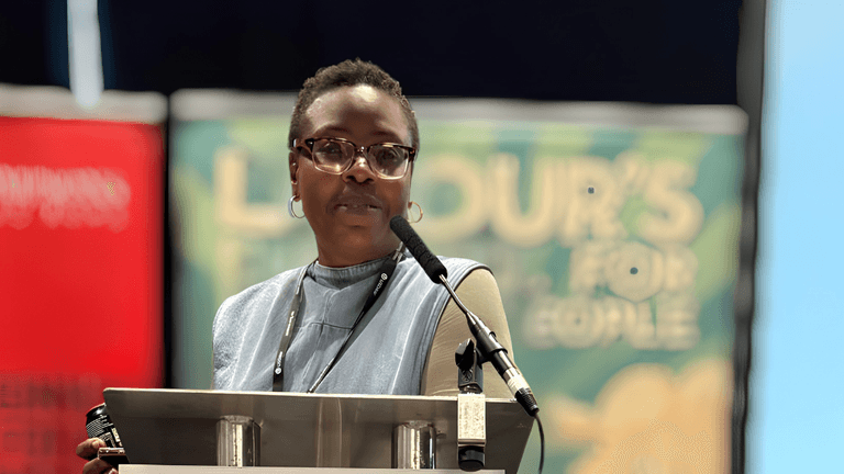 A woman with glasses speaks at a podium during a conference event