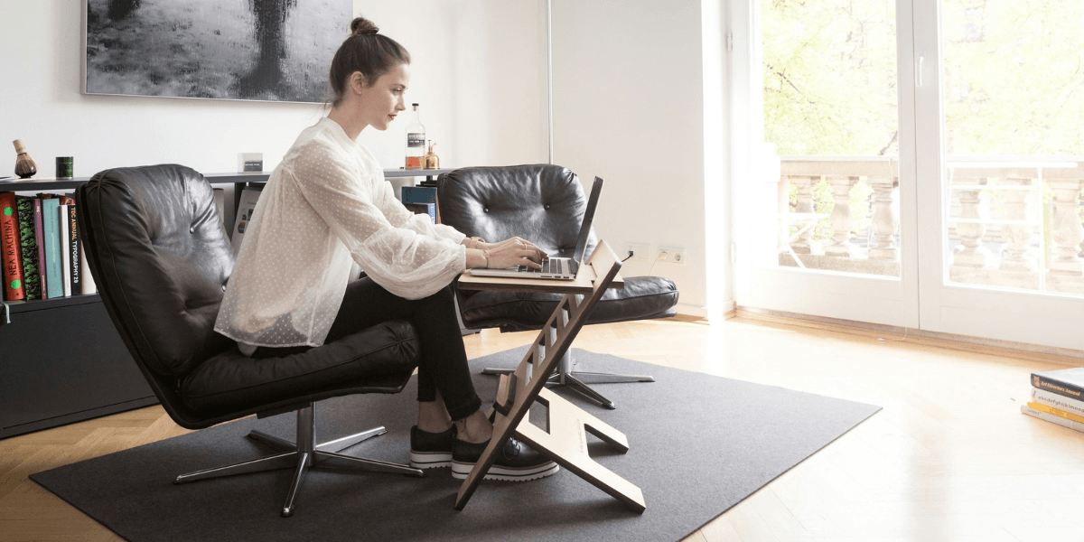 A woman working at a laptop seated in a modern lounge chair at home