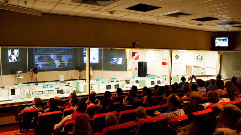 Interior of a control room with a large audience facing screens and displays