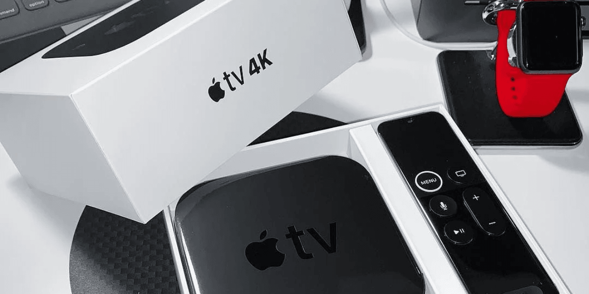 Apple TV 4K in its box with remote and an Apple Watch nearby