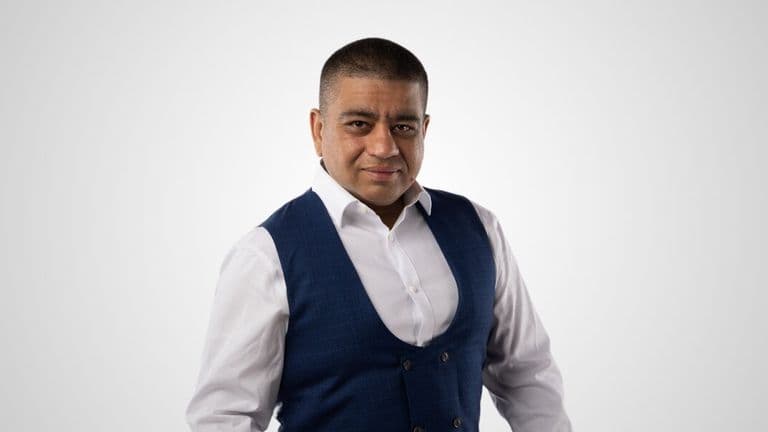 Imran Hussain, a professional and empathetic Fractional CFO, dressed in a white shirt and blue vest.