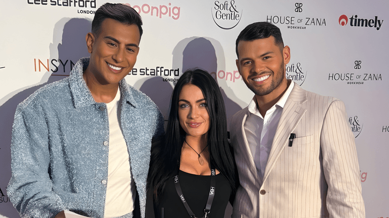 Three individuals posing at a beauty industry event with a backdrop featuring logos like Soft & Gentle and House of Zana.