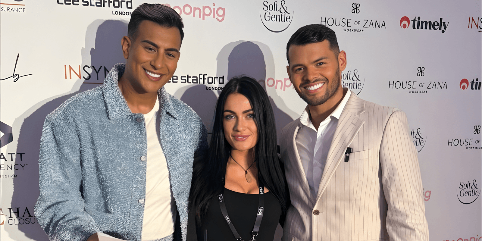 Three individuals posing at a beauty industry event with a backdrop featuring logos like Soft & Gentle and House of Zana.