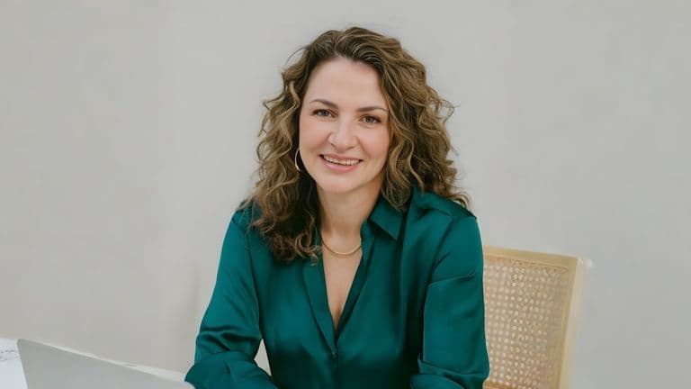 Simonetta Roma, a leadership coach, smiling confidently while sitting at a desk with a laptop.