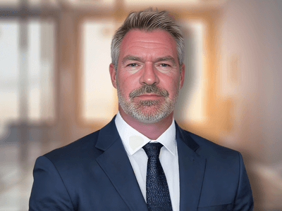 Professional businessman in navy suit with confident expression in modern office setting.