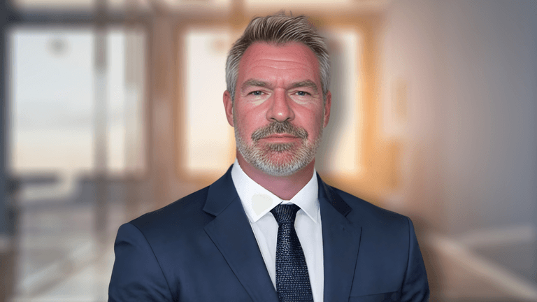 Professional businessman in navy suit with confident expression in modern office setting.