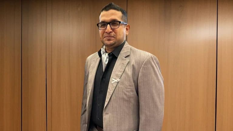 A man in a business suit stands confidently in front of wooden panels, symbolizing leadership and innovation in technology.