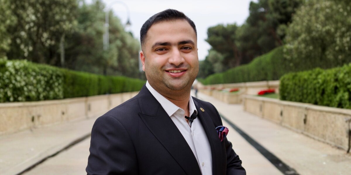 Dr. Hamza Tariq wearing a dark suit outdoors on a landscaped walkway.