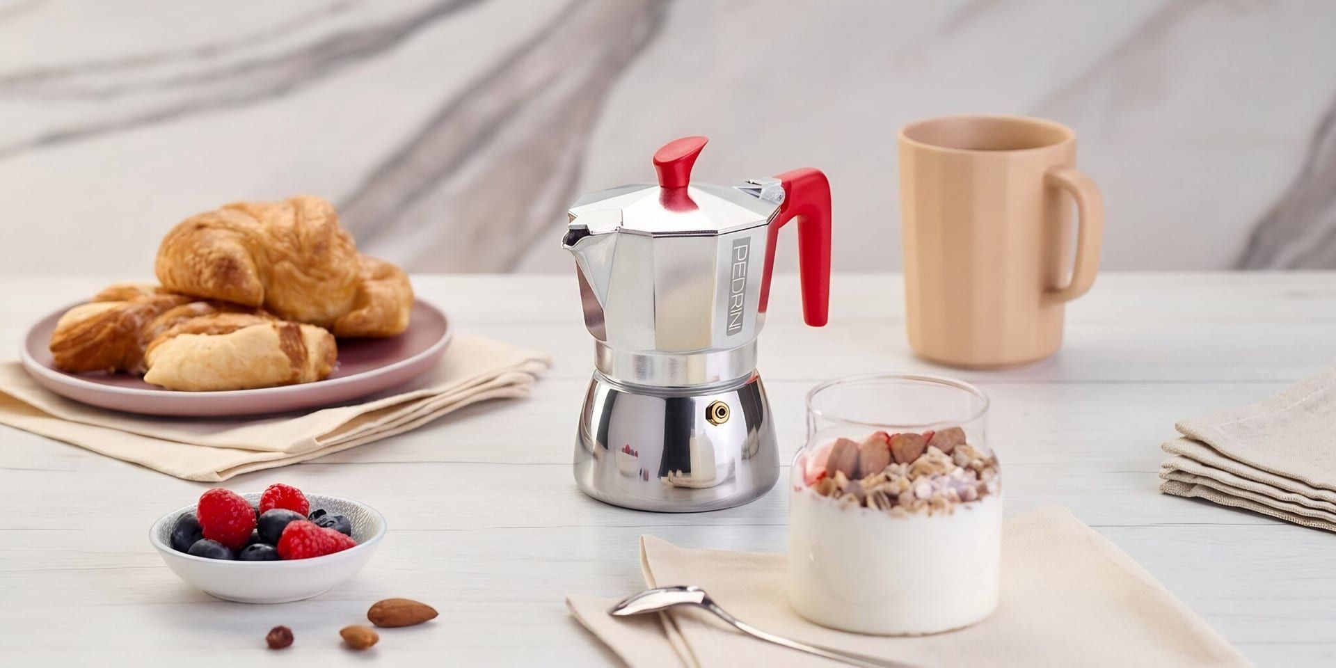 Pedrini moka coffee maker with pastries, yogurt, and berries on breakfast table.