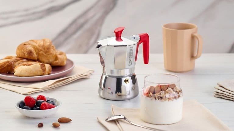 Pedrini moka coffee maker with pastries, yogurt, and berries on breakfast table.