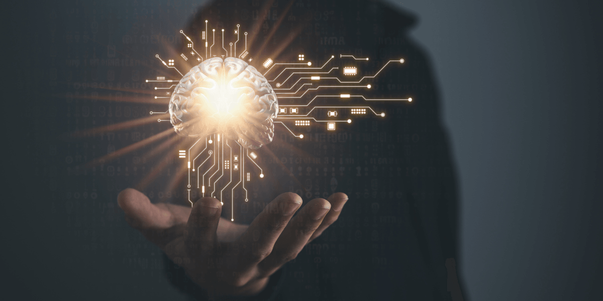 A hand holding a glowing brain connected to digital circuits, symbolizing artificial intelligence and advanced technology.