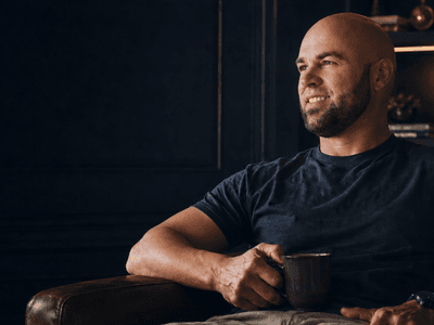 Veteran entrepreneur Adam Jacobs holding a coffee mug in a modern office, representing Astral & Root's wellness mission.