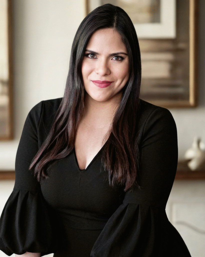 Lily Riefkohl smiling indoors wearing a black dress in a thoughtfully designed interior.